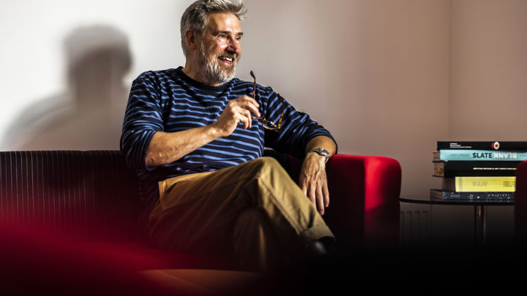 Simon Shaw, Creative Director at Hampton sitting on red sofa.