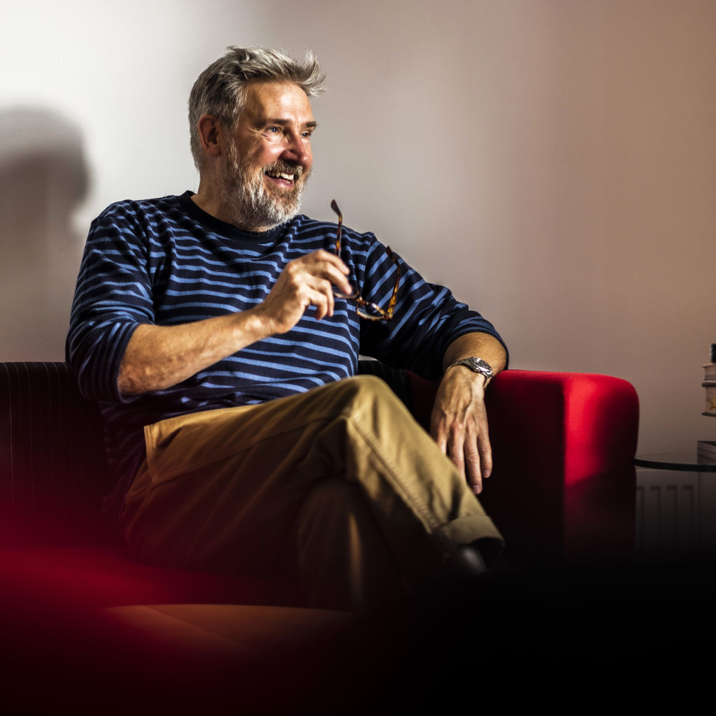 Simon Shaw, Creative Director at Hampton sitting on red sofa.